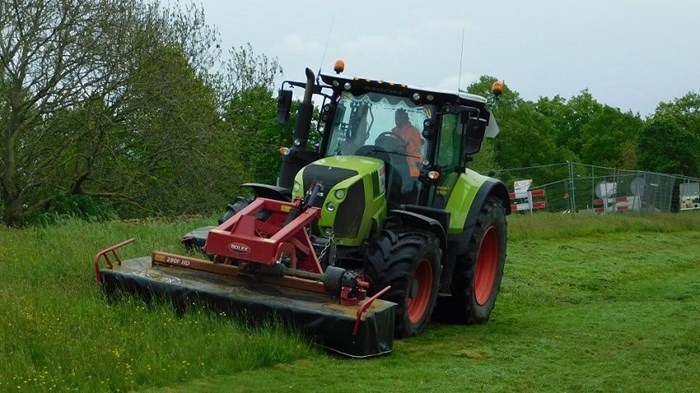 Een tractor maait het gras