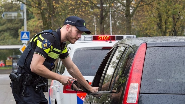 Politieagent spreekt automobilist bij verkeerscontrole
