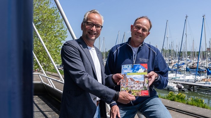 Foto Benno Ellerbroek - uitgever Ron Dol (l) overhandi eerste exemplaar van de stadsgids aan havenmeester Jos de Groot van de Grashaven.